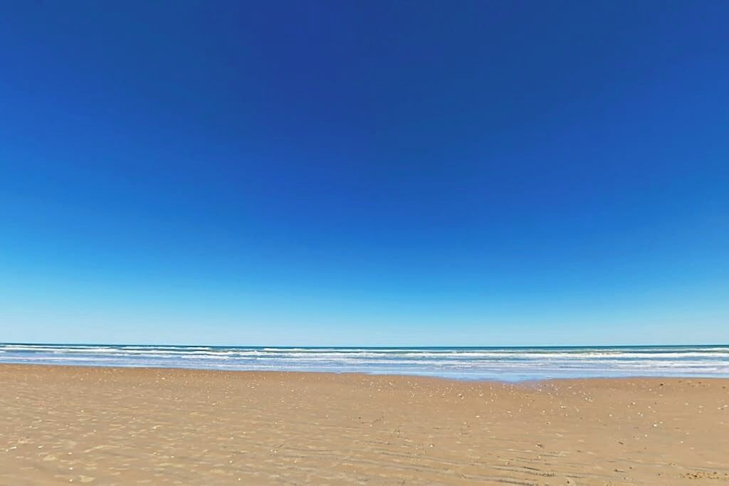 A beach with a clear sky and calm sea.