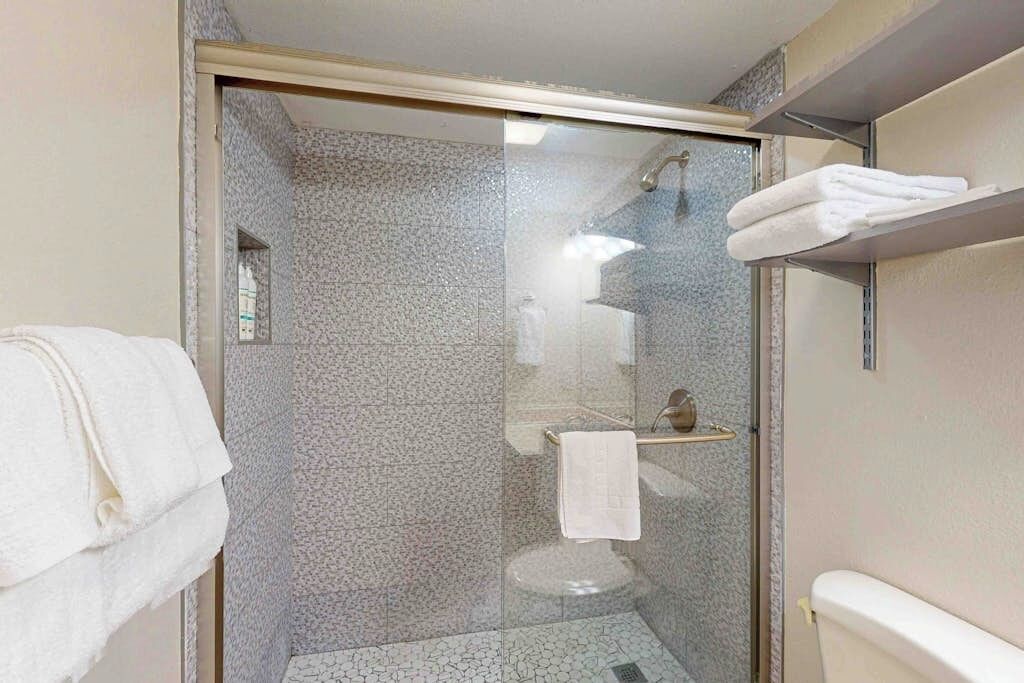 Ein Badezimmer mit einer Duschkabine, einem Handtuchhalter und einer Toilette.