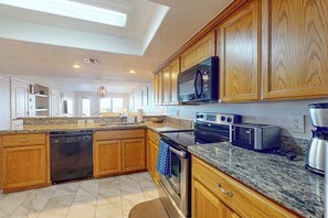 A modern kitchen with wooden cabinets, granite countertops, and stainless steel appliances. - Suntide II Condominiums #101 (South Padre Island)