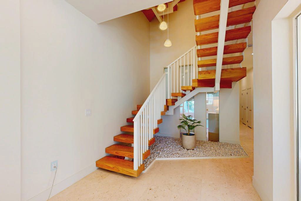 A staircase with wooden steps and white railings, leading to an upper floor.