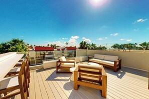 A rooftop terrace with outdoor seating and a clear view of the city skyline. - Wabi Sabi Home - Pool & Bay Views, Steps to Sand (South Padre Island)