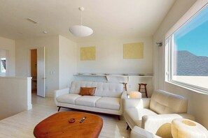 Ein modernes Wohnzimmer mit einer Couch, einem Couchtisch und einem großen Fenster.