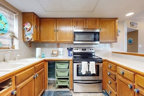 A kitchen with wooden cabinets, a stainless steel oven, and a microwave. - Beachview Condominiums #111 (South Padre Island)