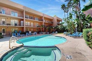 A hotel with a swimming pool, lounge chairs, and palm trees. - Beachview Condominiums #111 (South Padre Island)