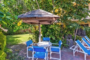 A patio with a wooden umbrella, blue chairs, and a table. - Ventura Condominiums #202 (South Padre Island)
