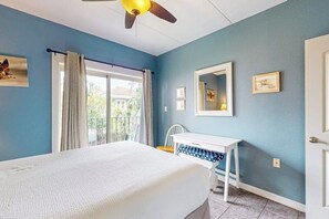 A bedroom with a bed, a desk, a chair, a ceiling fan, and a window with curtains. - Ventura Condominiums #202 (South Padre Island)