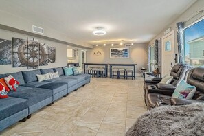 A spacious living area with a sofa, a leather couch, and a dining table with chairs. - Jamaican Waves - Waterfront, Hot Tub & Game Room (Jamaica Beach)