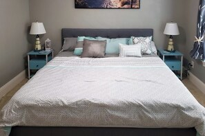 Ein Schlafzimmer mit einem großen Bett, zwei Nachttischen mit Lampen und einem Wandbild.