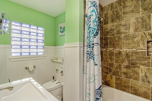 Ein Badezimmer mit einem weißen Waschbecken, einer Toilette, einer Badewanne und einem Duschvorhang mit blau-weißem Muster.