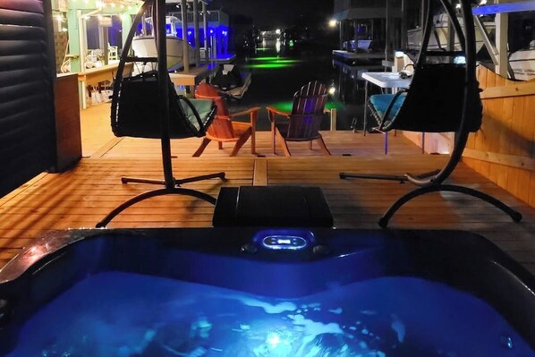 Ein Bereich mit Whirlpool, Sitzgelegenheiten und Blick auf ein Gewässer bei Nacht.