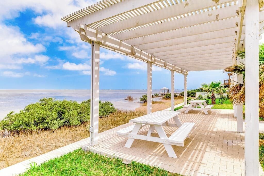 A covered outdoor area with picnic tables and a view of the sea.