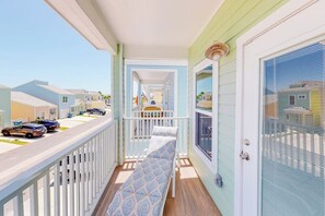 A balcony with a bench, a view of the street, and a door with a window. - Las Joyas Bayview Home #217 (Port Isabel)