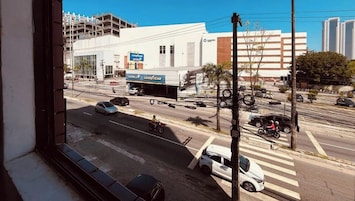 Vista da rua com uma loja Goodyear de pneus, faixa de pedestres e um prédio em construção.