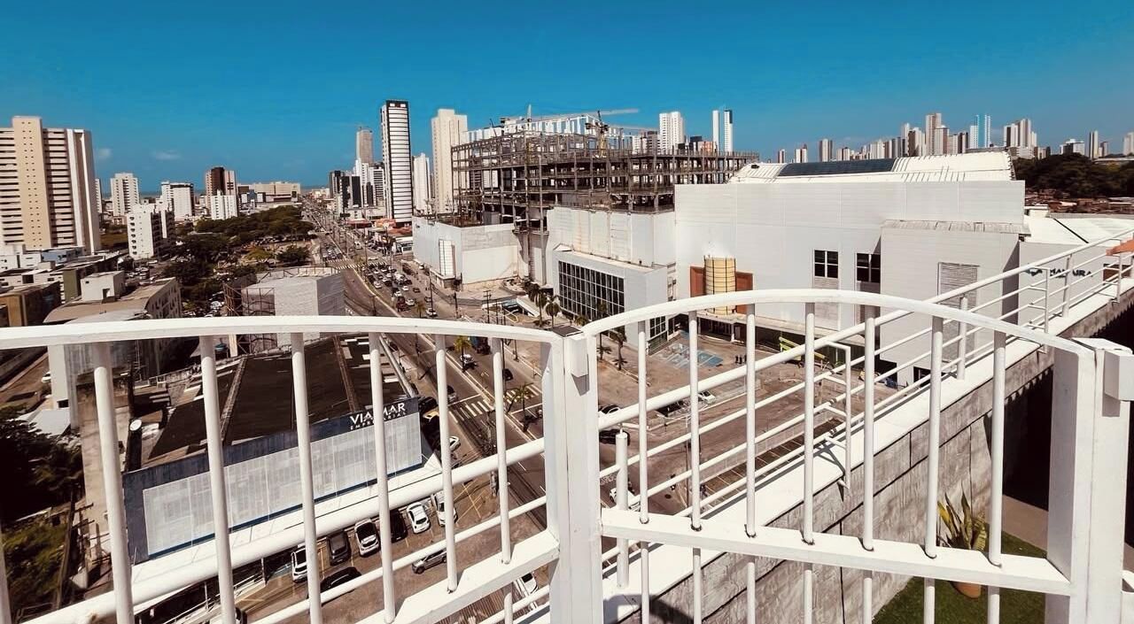 Um edifício alto com vista para o horizonte urbano, incluindo uma ponte e um estacionamento.