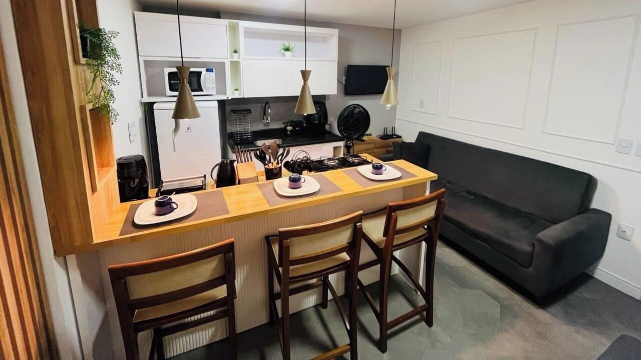 A compact kitchen with a central island, a dining area with chairs, and a sofa.