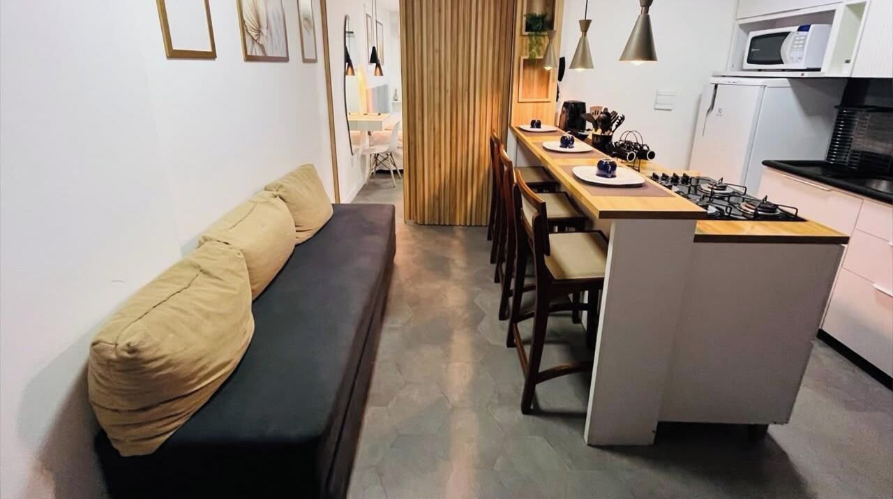 A compact living space with a sofa, dining table, chairs, and a kitchenette.