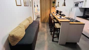 A compact living space with a sofa, dining table, chairs, and a kitchenette.