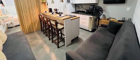 Una cocina moderna con una isla central, muebles blancos y un televisor de pantalla plana montado en la pared.