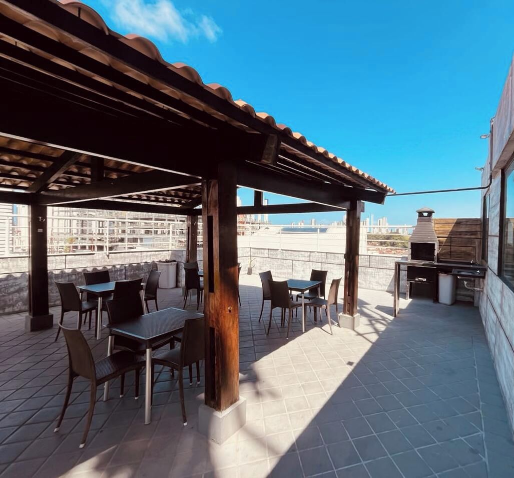 An outdoor patio with tables and chairs, a pergola, and a barbecue grill.