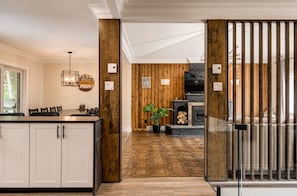 Una cocina moderna con una pared de acento de madera, un comedor con sillas y una chimenea.