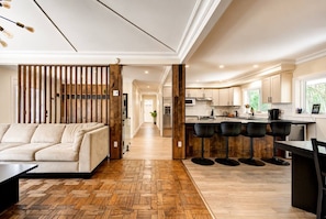 A modern kitchen with a central island, bar stools, and a dining table.