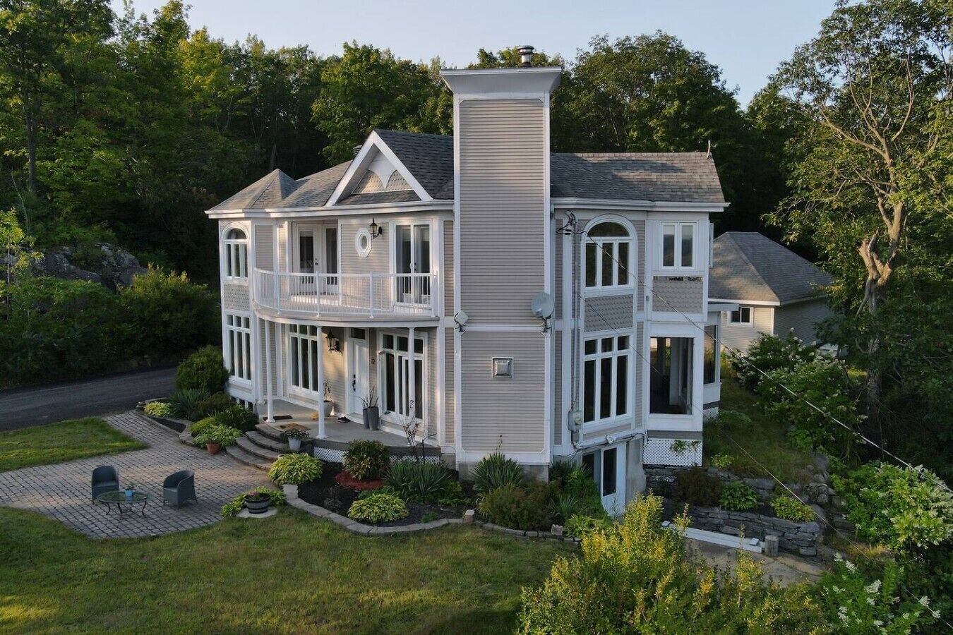 A two-story house with a large front porch, a chimney, and a well-maintained garden.