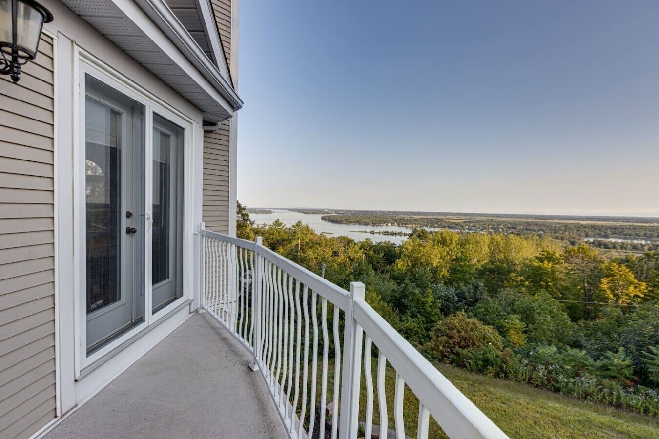 A residential building with a balcony overlooking a natural landscape and a body of water.