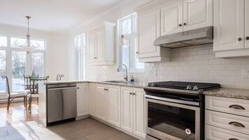 A kitchen with white cabinets, a stainless steel dishwasher, a double oven, and a granite countertop.