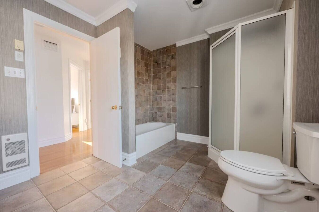 A bathroom with a toilet, a bathtub, and a shower enclosure.