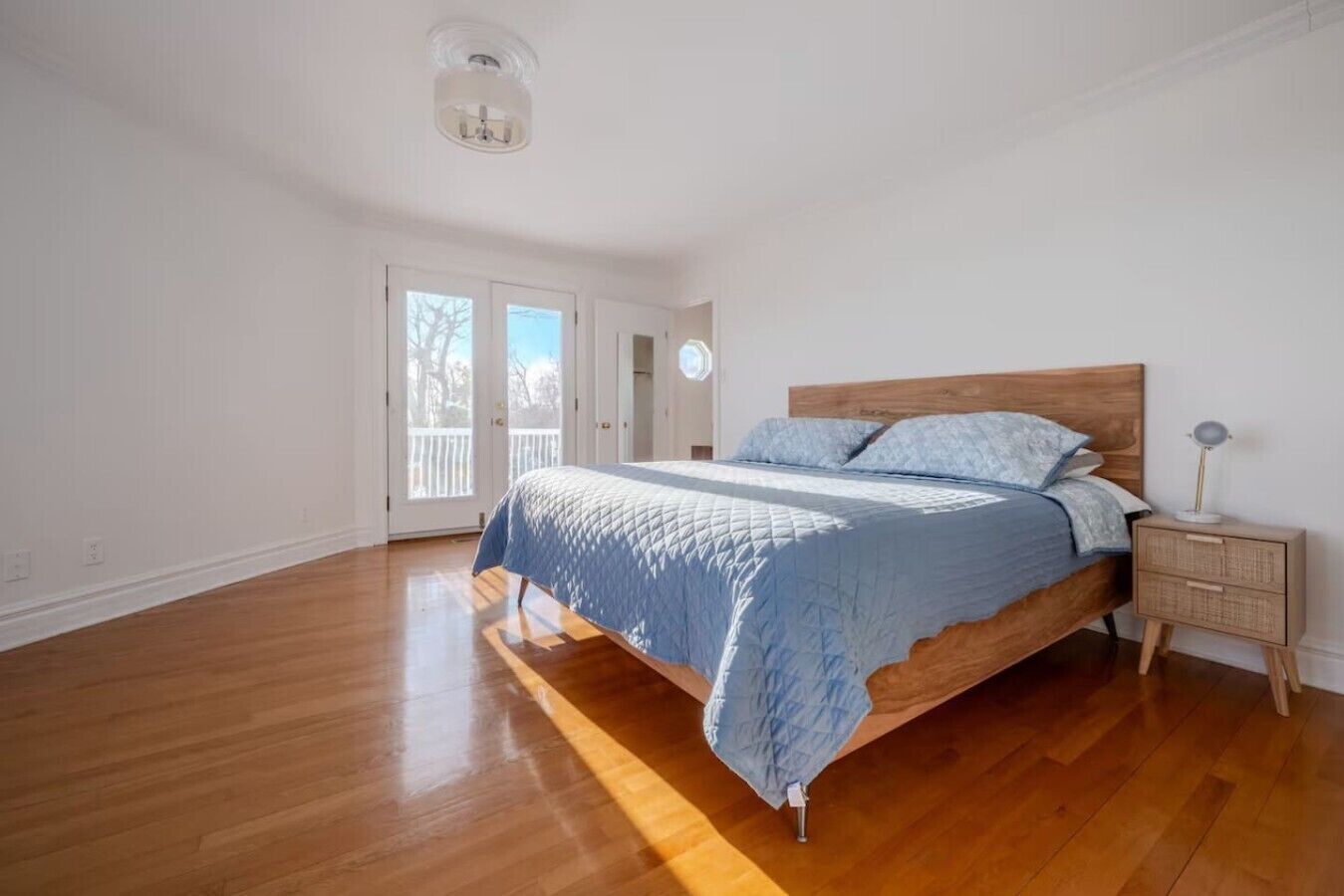 Un dormitorio con una cama de madera, una mesita de noche y una lámpara en el techo.