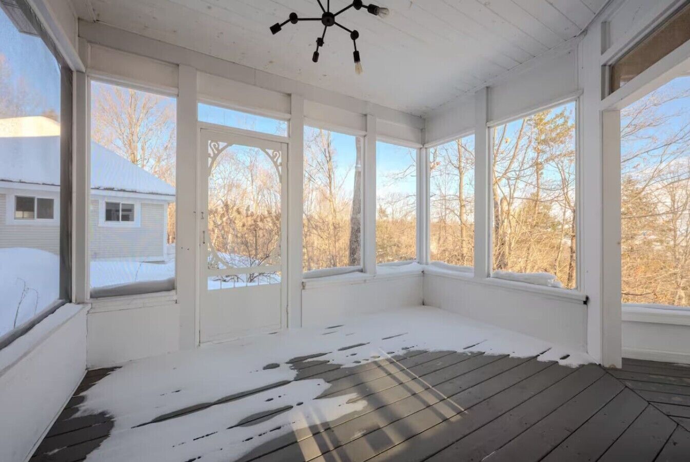Una habitación con ventanas amplias, piso de madera y un ventilador de techo.