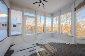 Una habitación con ventanas amplias, piso de madera y un ventilador de techo.