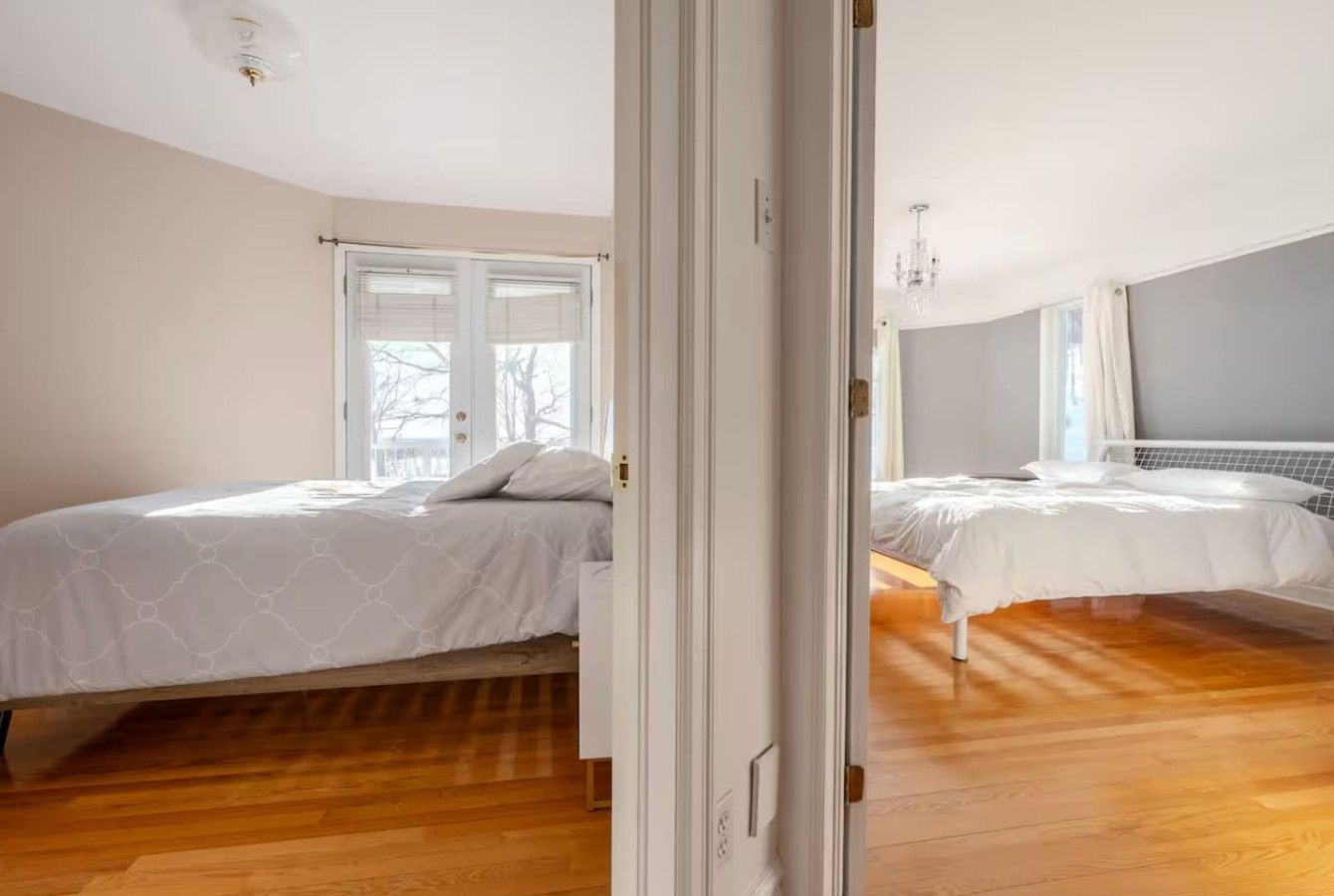 Un dormitorio con dos camas, suelo de madera y un ventanal grande.