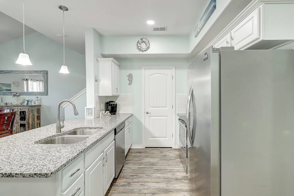 A kitchen with granite countertops, stainless steel appliances, and white cabinetry.