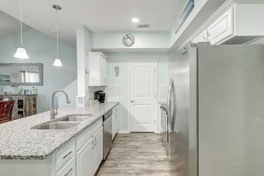 Una cocina con encimeras de granito, electrodomésticos de acero inoxidable y muebles de cocina blancos.