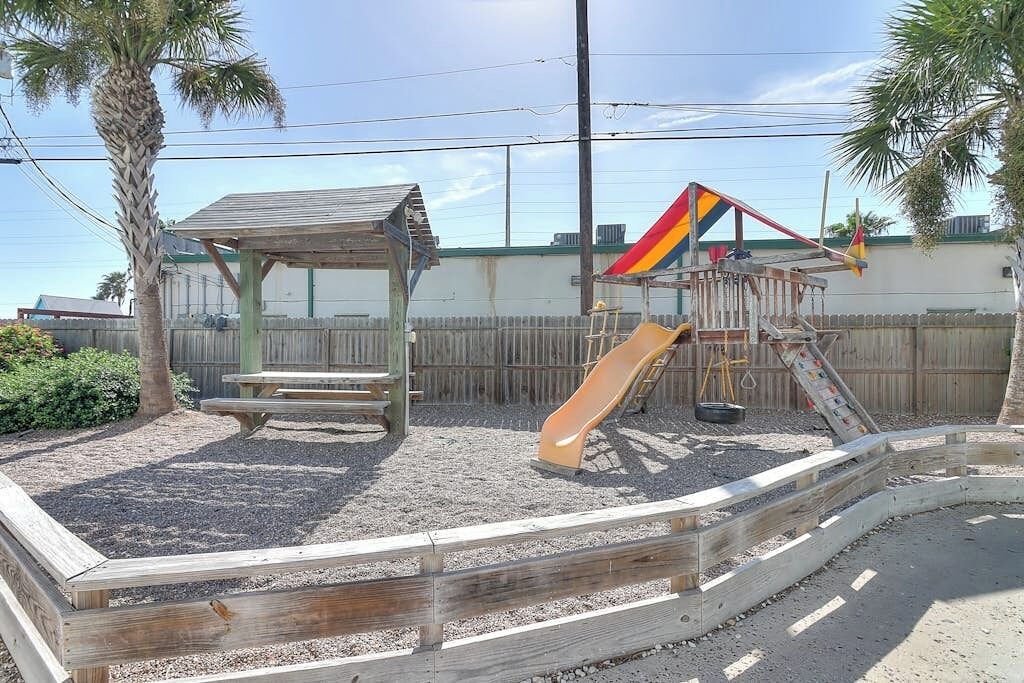 A playground with a slide and a picnic table.