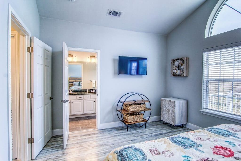 Un dormitorio con cama, televisor, radiador y puerta que da al baño.