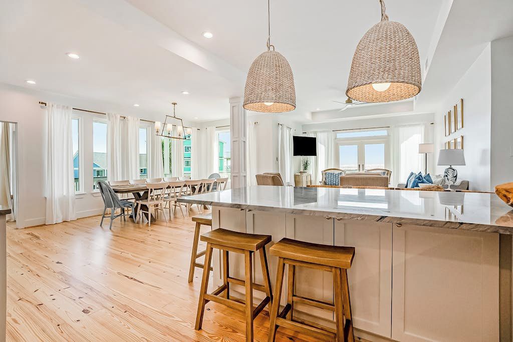 Una cocina amplia con una isla grande, taburetes de madera e iluminación colgante.