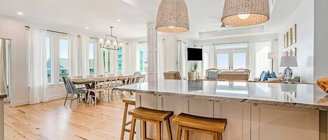 Una cocina amplia con una isla grande, taburetes de madera e iluminación colgante.