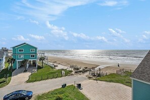 Una propiedad costera con vista a la playa, un camino de entrada pavimentado y un edificio de dos pisos.