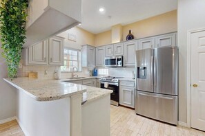 A kitchen with white cabinetry, stainless steel appliances, and a granite countertop. - Water House Getaway - Patio on the Water, Dogs OK (Corpus Christi)