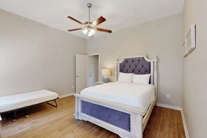 Ein Schlafzimmer mit einem Bett, einer Bank, einem Deckenventilator und einer Tür.