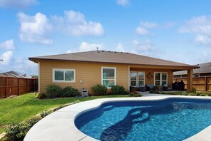 Ein Wohnhaus mit Swimmingpool, überdachter Terrasse und umzäuntem Garten.