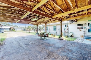 A covered outdoor area with a table and chairs, a building with a number '315' sign, and a clear sky. - Flip Flop Inn - Patio, 2 Blocks from the Bay (Rockport)