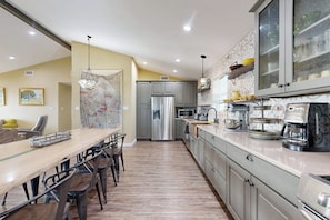 A modern kitchen with a dining area, stainless steel appliances, and a patterned backsplash. - Copano Ridge Dream A (Rockport)
