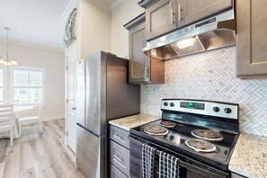 Uma cozinha com eletrodomésticos de aço inoxidável, painel de backsplash em padrão losango e piso em padrão losango.