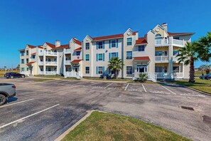A multi-story hotel with a parking lot in front. - Beach Club 172 - Balcony & Pool, Close to Beach (Corpus Christi)