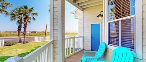 A porch with two chairs, a door, and a window with blinds.