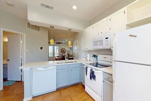 A kitchen with white cabinets, a microwave, a stove, and a sink. - Beach Club 172 - Balcony & Pool, Close to Beach (Corpus Christi)