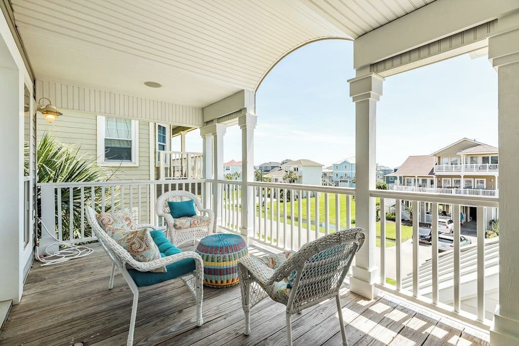 A covered porch with wicker furniture and a view of the neighborhood.